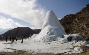 A towering ice stupa in Ladakh, reflecting sunlight against a clear blue sky.